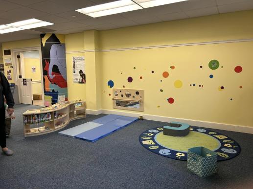 The Library's new Baby Zone featuring low shelves, toys, a mirror, and soft space to play.