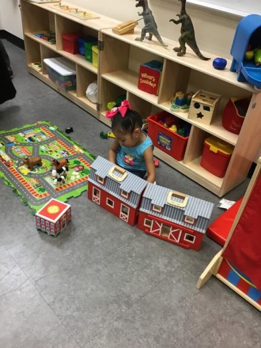 Toddler playing with barn toy in dramatic play area of Family Place Library