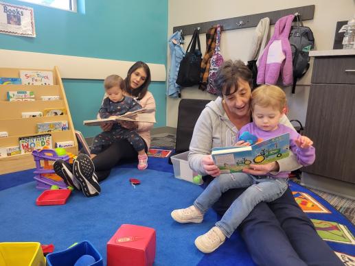 A mother and grandmother share a story with their little ones.