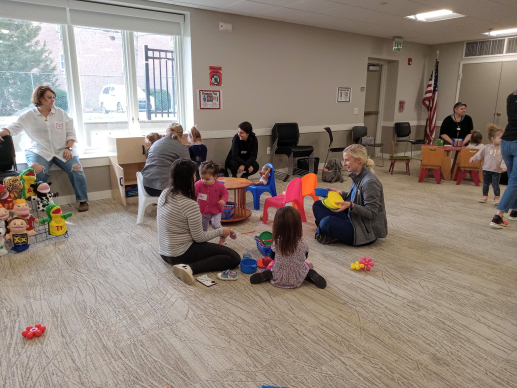 Caregivers and children playing with a toy kitchen