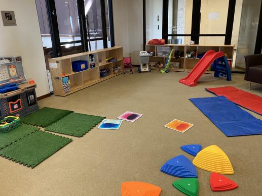 Play area with slide, tool bench, stepping stones and tiles, tumbling matts, and other toys.