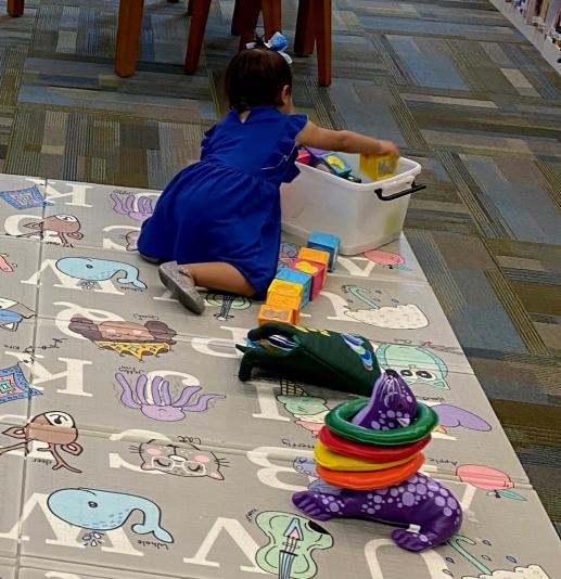 Child playing with learning toys on an alphabet mat.