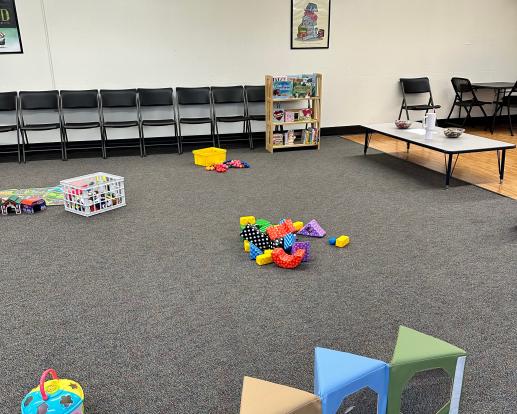 A small area of the Parent Child Workshop including books, blocks, cars, and paper with crayons