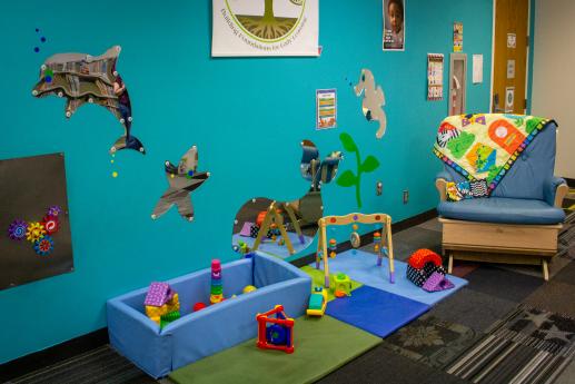 Photo of Baby Area with play mat, baby toys, mirror sea creatures, and a cushioned glider bench for nursing or reading.