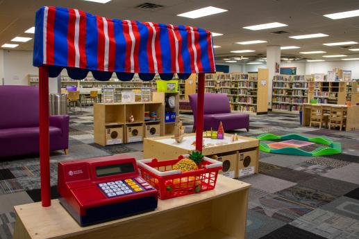 Photo of Market Stand, manipulative table with blocks, shelves of toys, balance beam, and writing center.