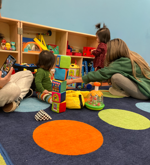 parents and children on bright carper playing with toys. 