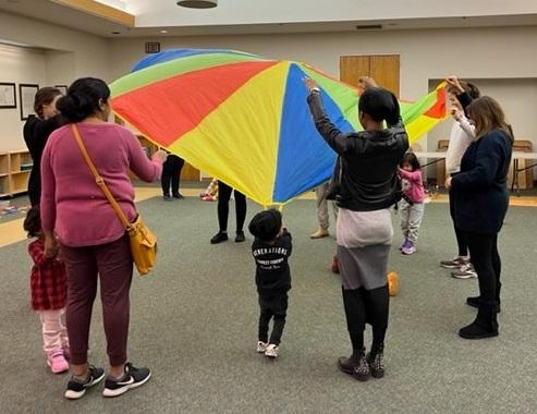 Families playing with a parachute at Parent/Child Workshop