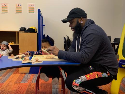 Father doing puzzle with child sitting at a table.