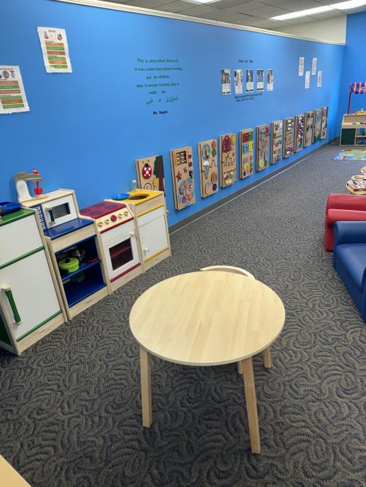 Image of a play kitchen area and a long blue wall with sensory boards along the side.