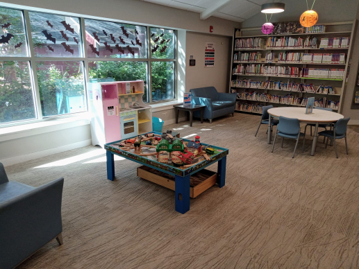 Play area with toy kitchen, train table, baby books, and parenting books