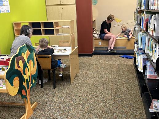 Children and caregivers using writing table and quiet puzzle space in children's room in the Mt Lebanon Public Library