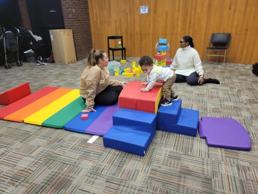 Child climbing on toddler gym and parents talking