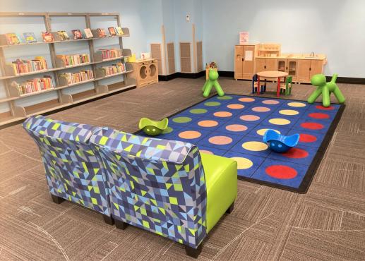 Photo of passive programming area including dramatic play sets and seating for caregivers. 