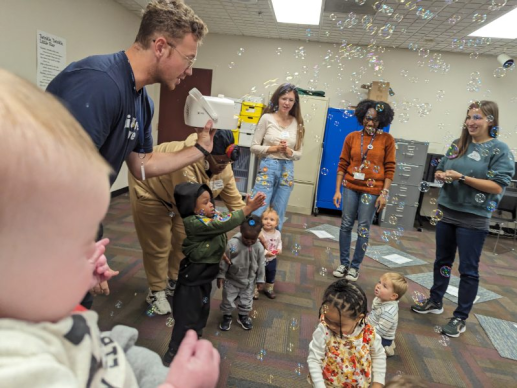 Adults watch as children play with bubbles.