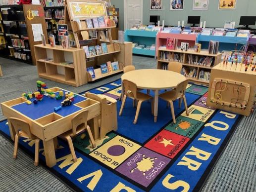 An image of our displays of board books and new children's books, our lego table, the children's carpet, the small table and chairs, and the fidget cube